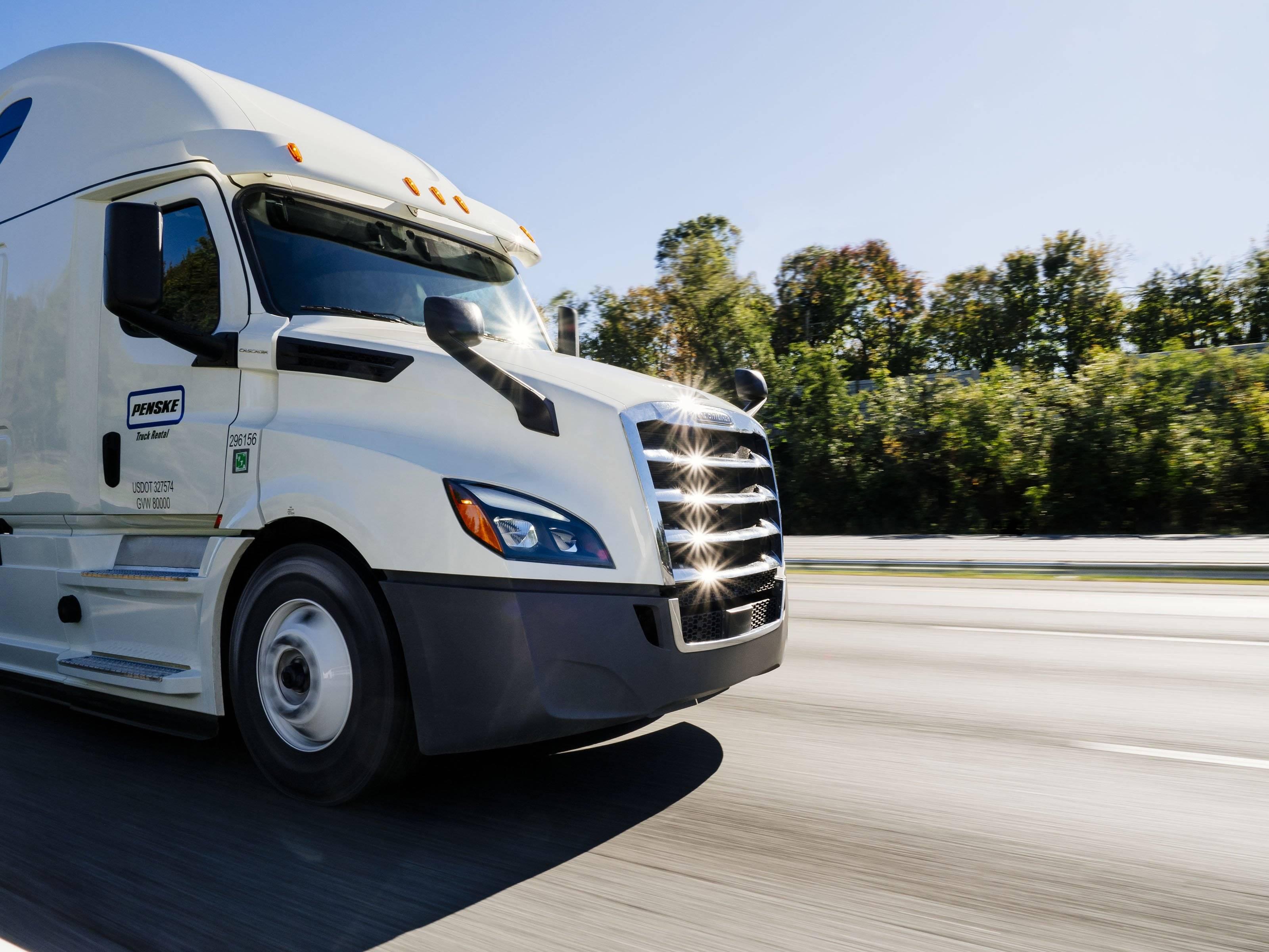 A closeup of a white Penske semi-truck tractor on the road.