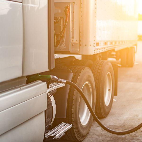 A diesel pump stuck into the fuel tank of a white semi-truck.