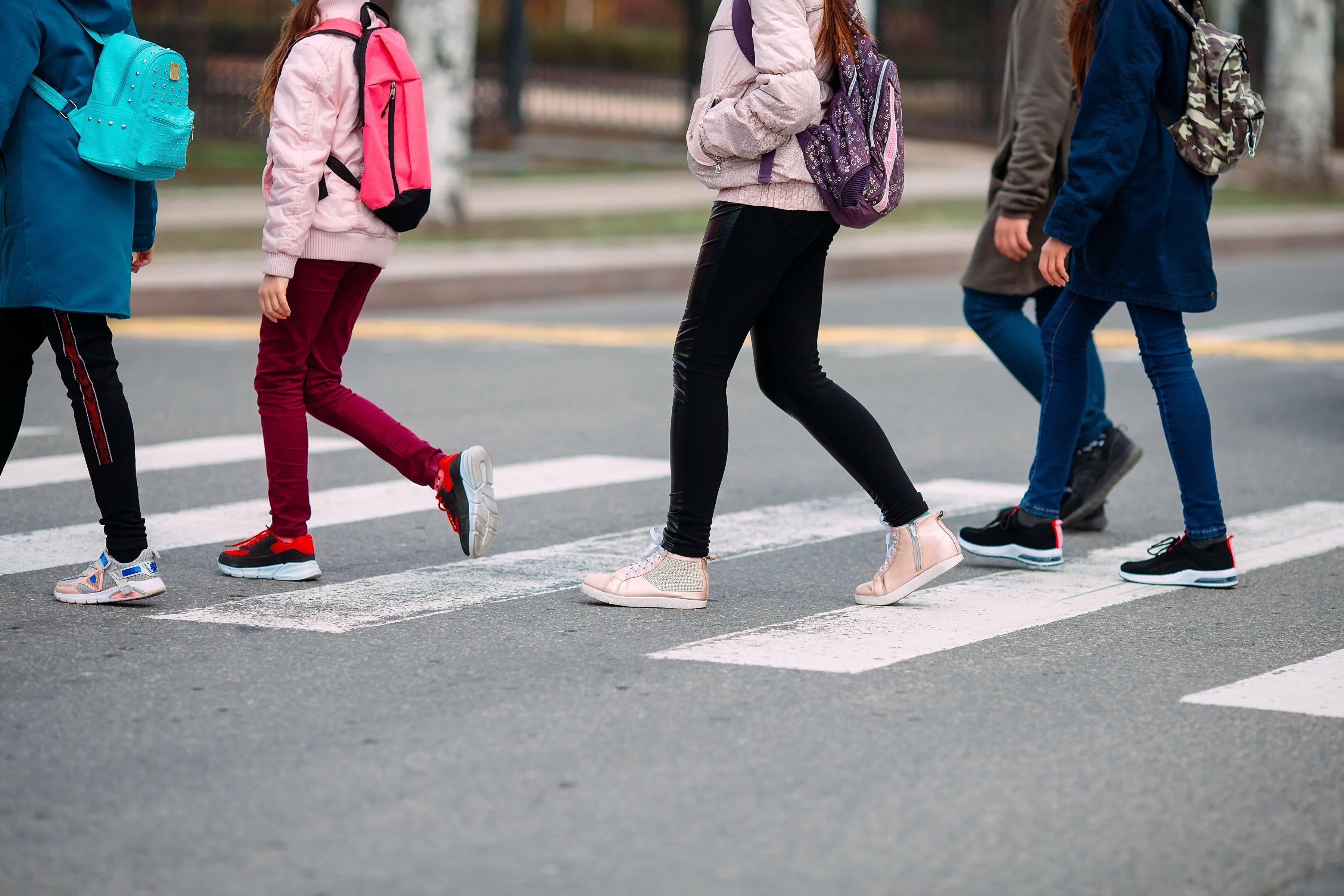 A group of kids with backpacks cross the street on the way to school.
