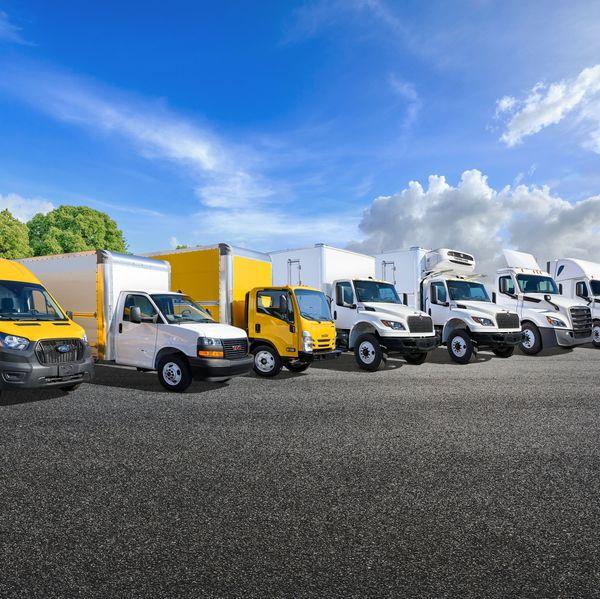 A lineup of yellow and white Penske trucks in a parking lot.