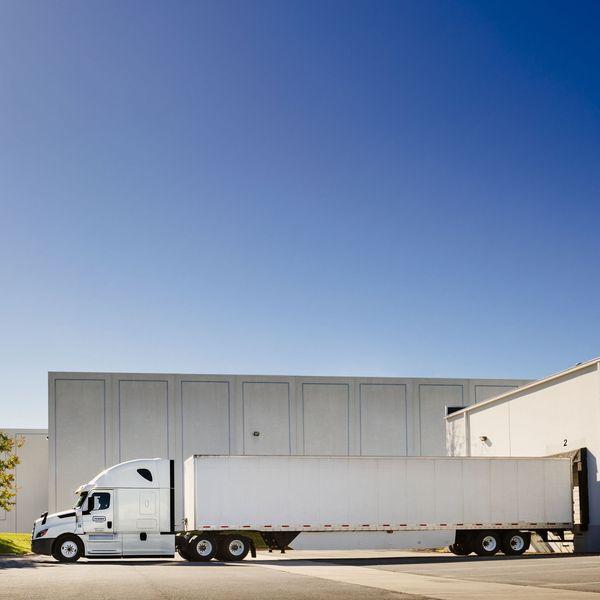 A penske semi-truck and trailer at a loading dock.
