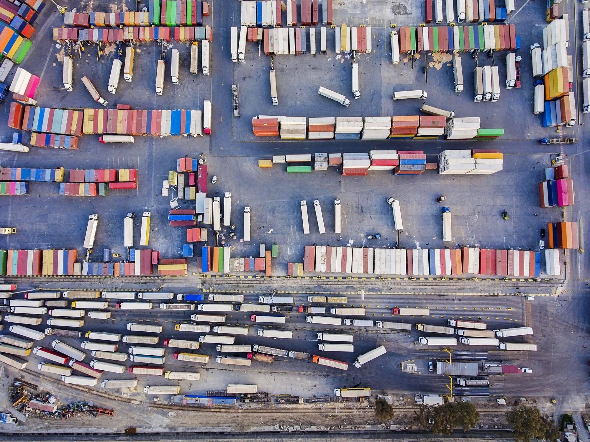 An above view looking down into a very busy shipping yard with containers and trucks lined up.