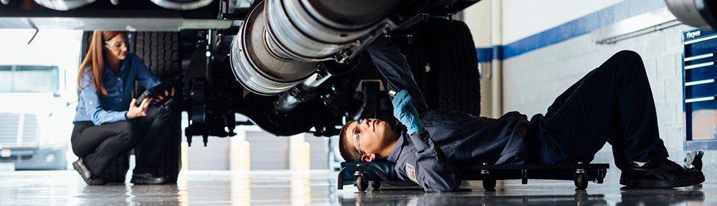  Two technicians servicing the underside of a truck